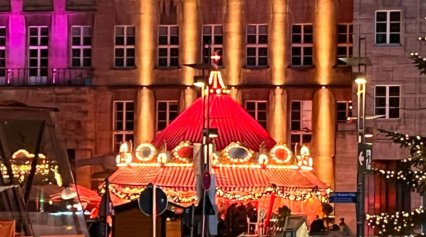 Das Bierkarussell bei Nacht, beleuchtet, vor einem angestrahlten Gebäude