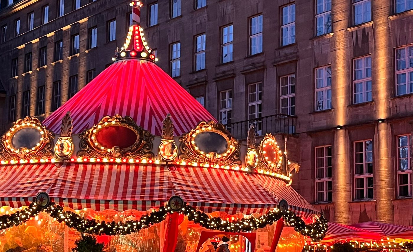 Das Bierkarussell mit Tannengirlanden vor dem Rathaus, Gäste sitzen am Tisch